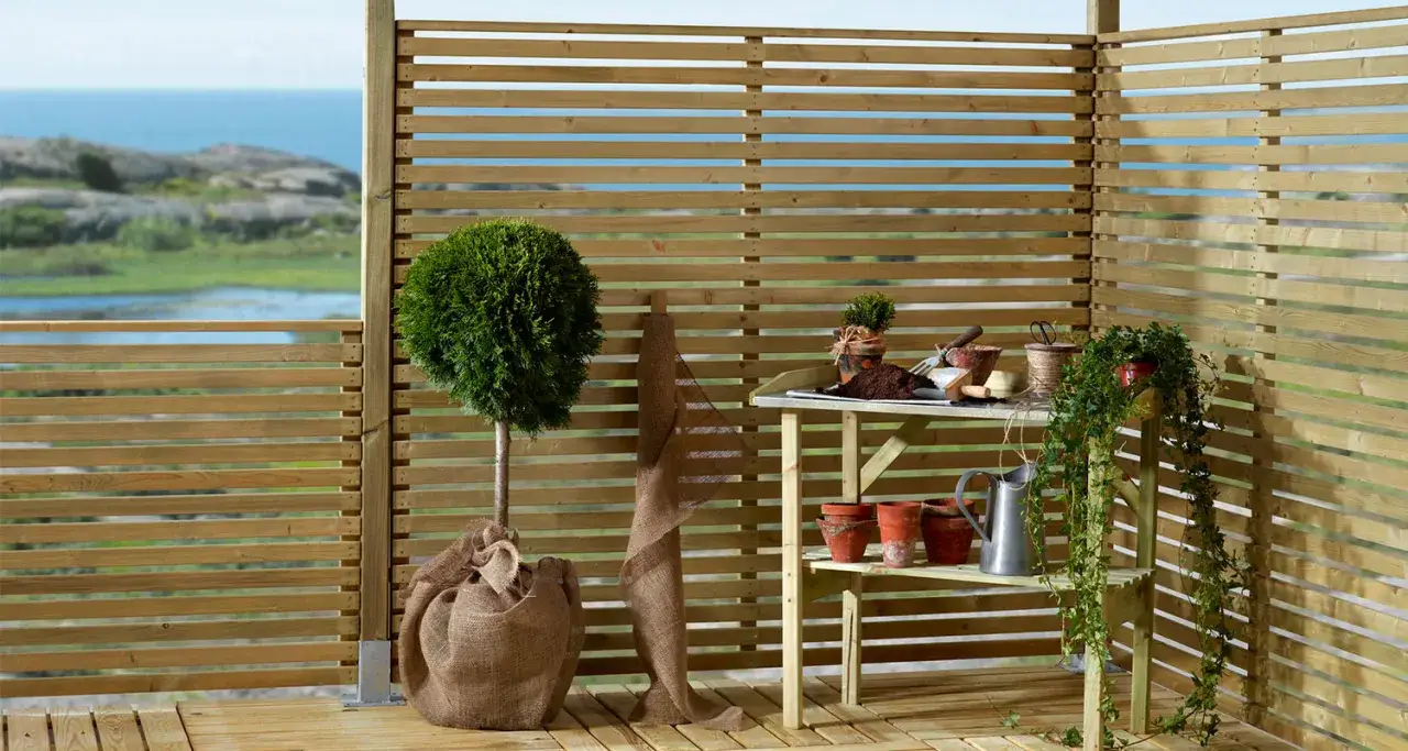 En altan med tr&auml;staket, en rundad buske, krukor och tr&auml;dg&aring;rdsredskap. En ritning f&ouml;r att bygga vindskydd skulle kunna se ut s&aring; h&auml;r.