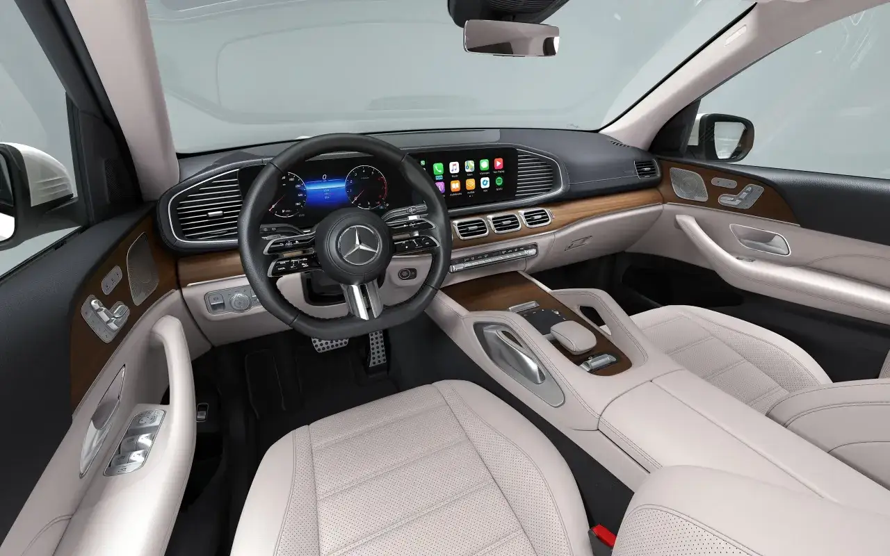 Wnętrze luksusowego **Mercedes GLS 580** z jasną tapicerką, drewnianymi wstawkami i nowoczesnym ekranem multimedialnym.