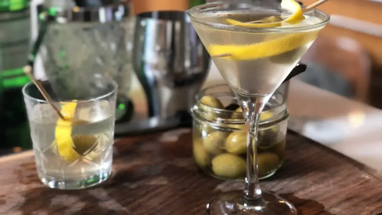 Un verre de dry martini, garni d'une torsade de citron et d'olives, pr&ecirc;t &agrave; &ecirc;tre d&eacute;gust&eacute;. La recette parfaite pour un ap&eacute;ritif chic.