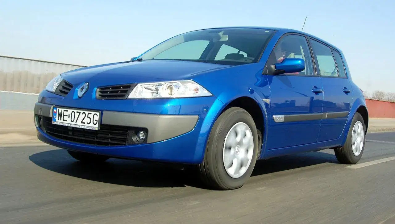 Niebieski Renault Megane 2 1.6 16v z tablicą WE 0725G jedzie po drodze.