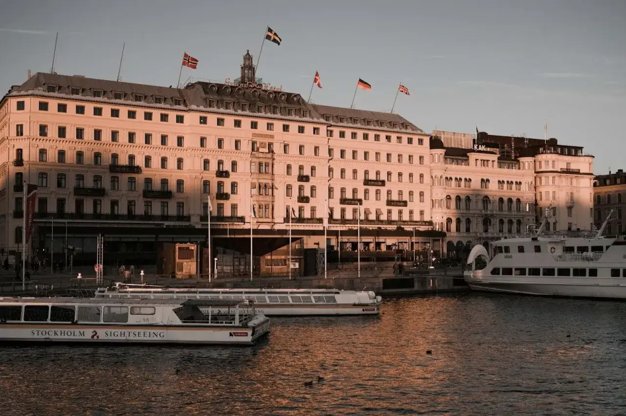 Vackert kvällsljus över Grand Hôtel i Stockholm. Perfekt för en romantisk date night Stockholm med utsikt över vattnet och båtarna.
