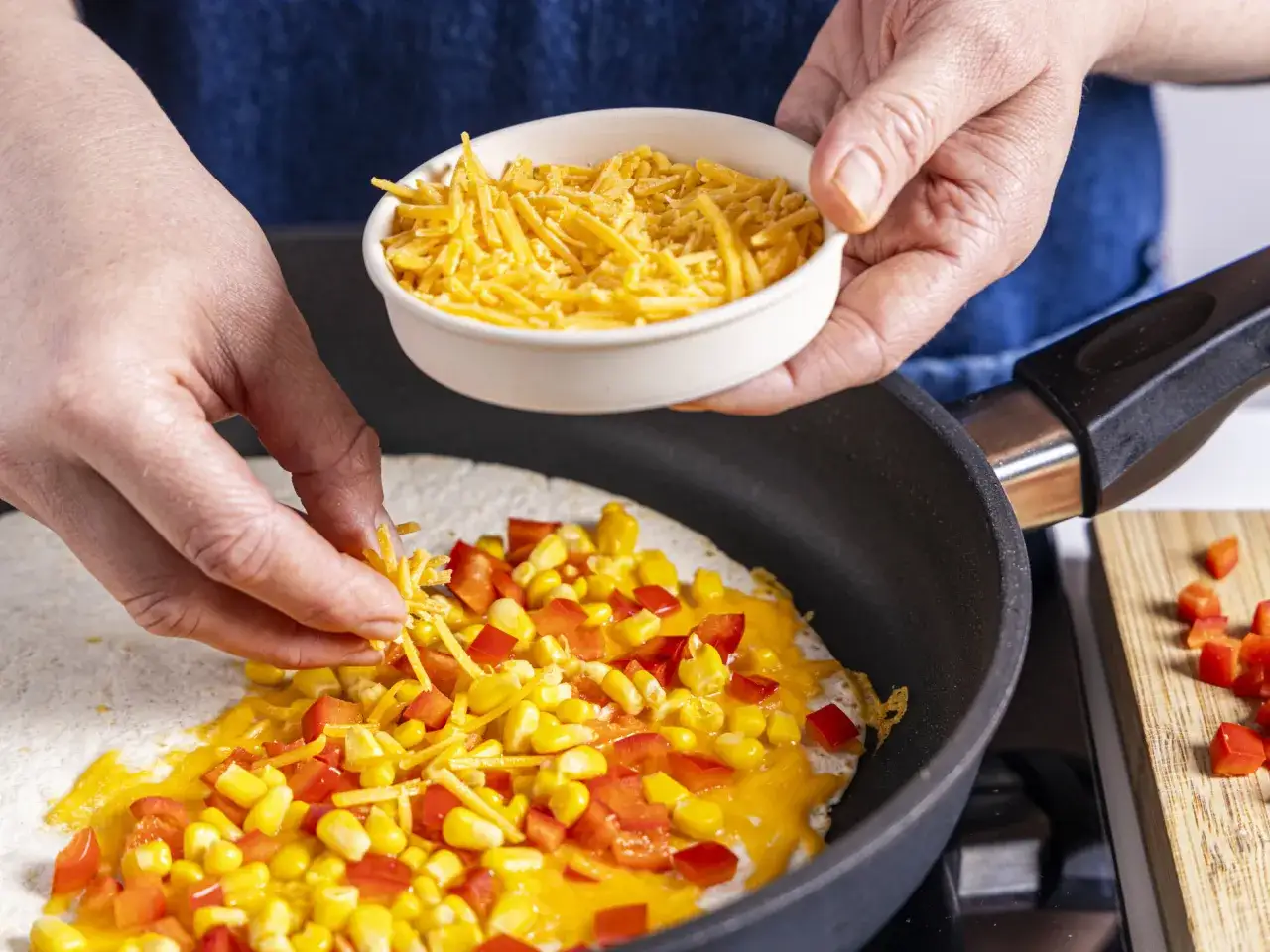 H&auml;nde belegen Tortilla mit Mais, Paprika und K&auml;se f&uuml;r ein leckeres Quesadillas Rezept.
