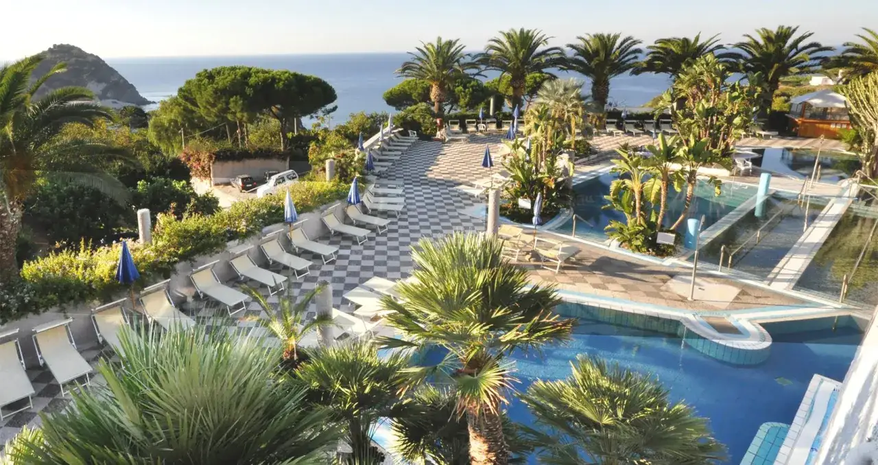 Piscine e lettini alle terme Sant'Angelo Ischia, con palme e vista mare.