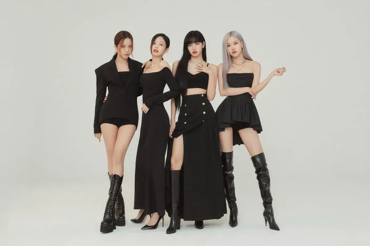 Członkowie BLACKPINK w czarnych, eleganckich strojach pozują do zdjęcia.