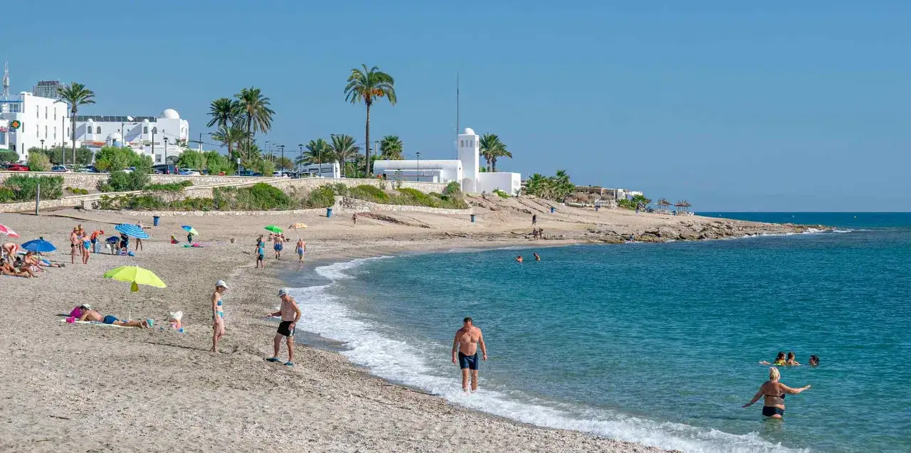 Gente disfrutando de las mejores playas de Mojácar, con aguas cristalinas y el sol brillando.