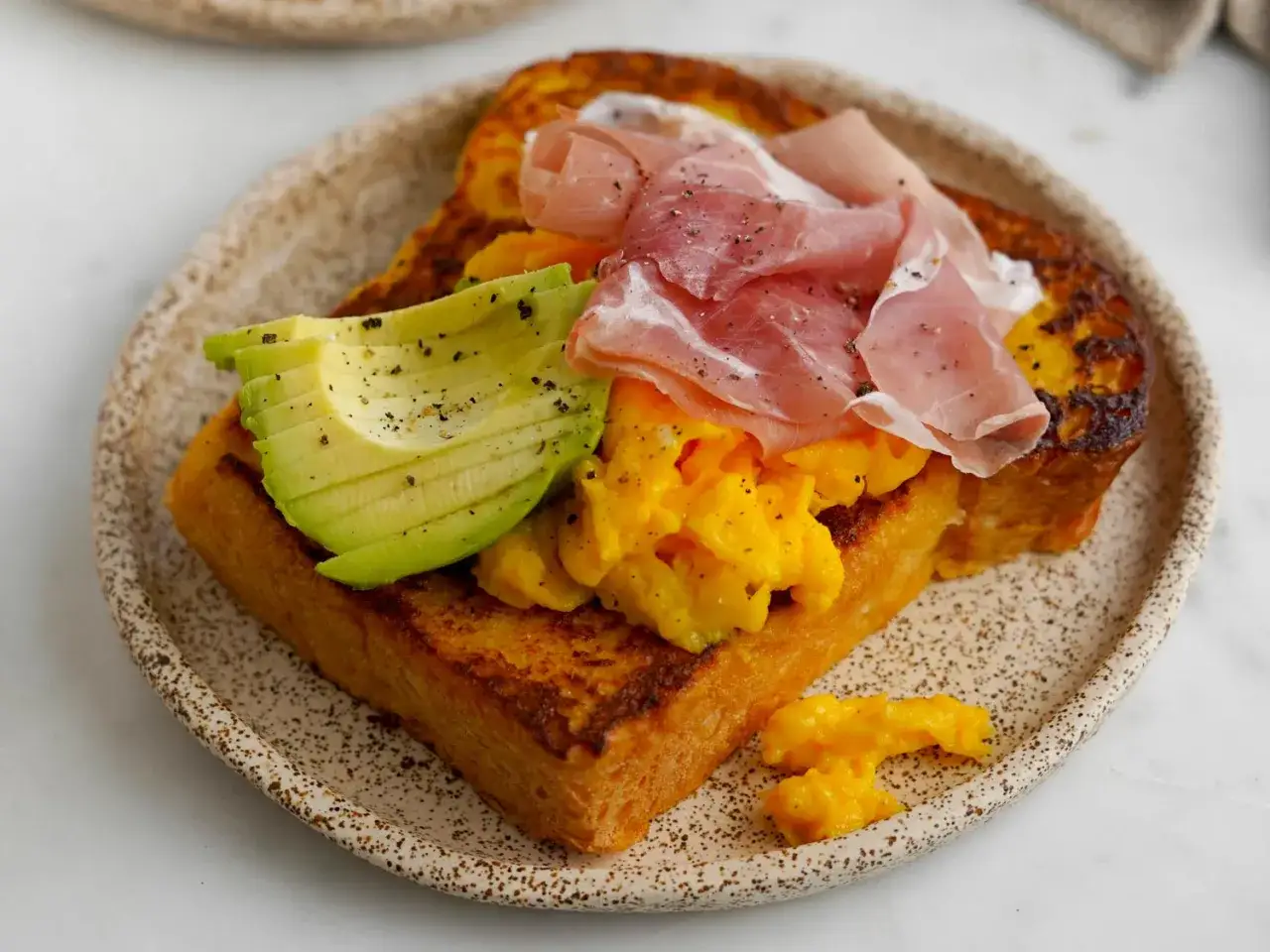 Herzhaftes French Toast mit Rührei, Avocado und Schinken. Ein köstliches Frühstück oder Brunch.