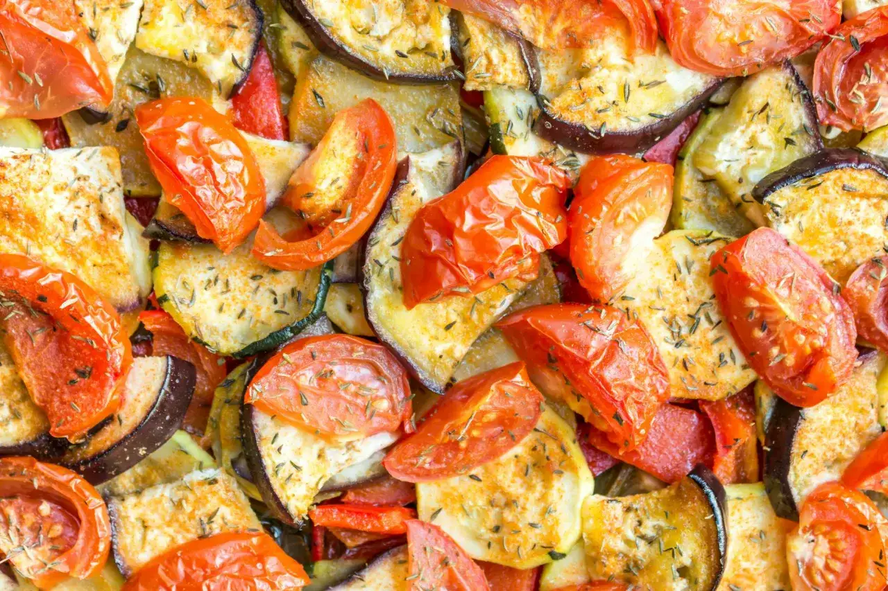 Un plat color&eacute; de ratatouille recette, avec des aubergines, courgettes, poivrons et tomates r&ocirc;tis, parsem&eacute; d'herbes.