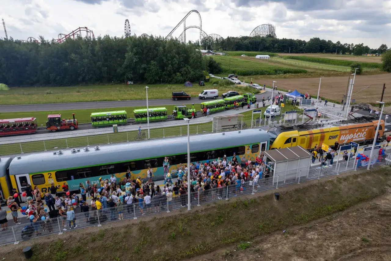 Pociąg do Energylandii przywozi tłumy turystów. W tle widać kolejki górskie.