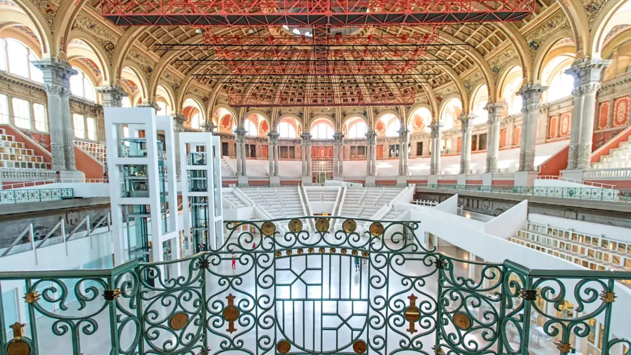 Wnętrze muzeum narodowego w Barcelonie z imponującą kopułą, kolumnami i nowoczesnymi windami.