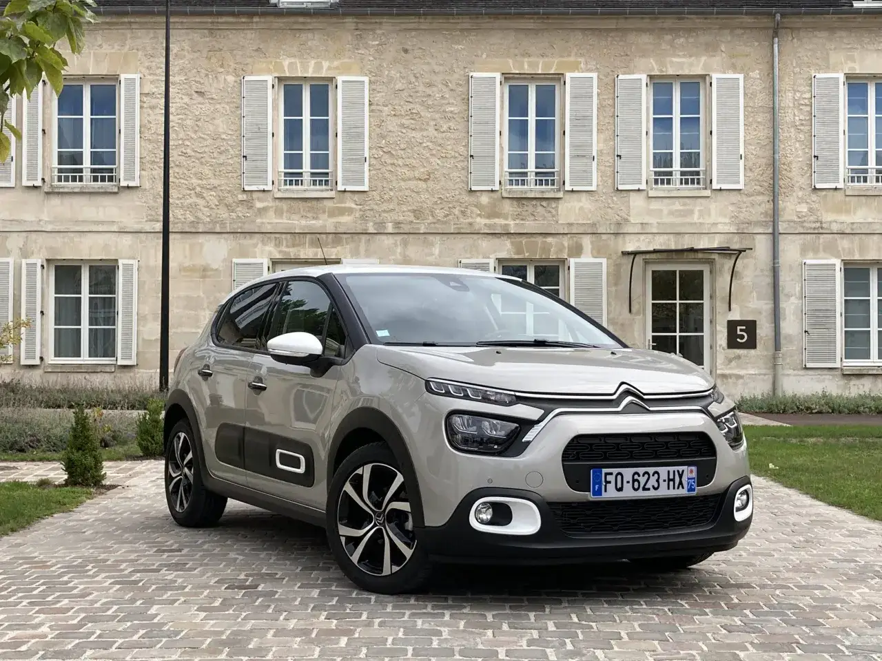 Citroën C3 gris stationnée devant une maison en pierre. Les jantes alliage et la taille pneu citroën c3 sont bien visibles.