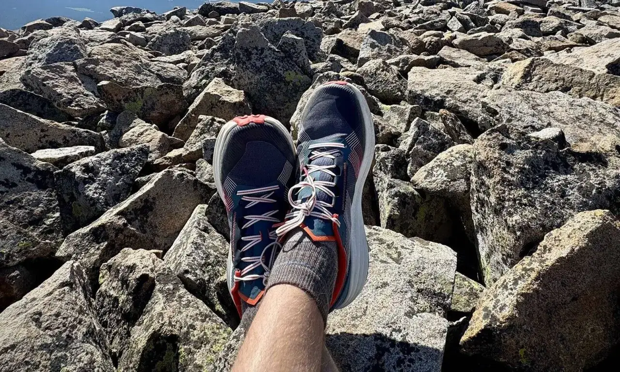 Gotowe buty w góry czekają na szczycie. Stopy w wygodnych butach odpoczywają na kamieniach po trudach wspinaczki.