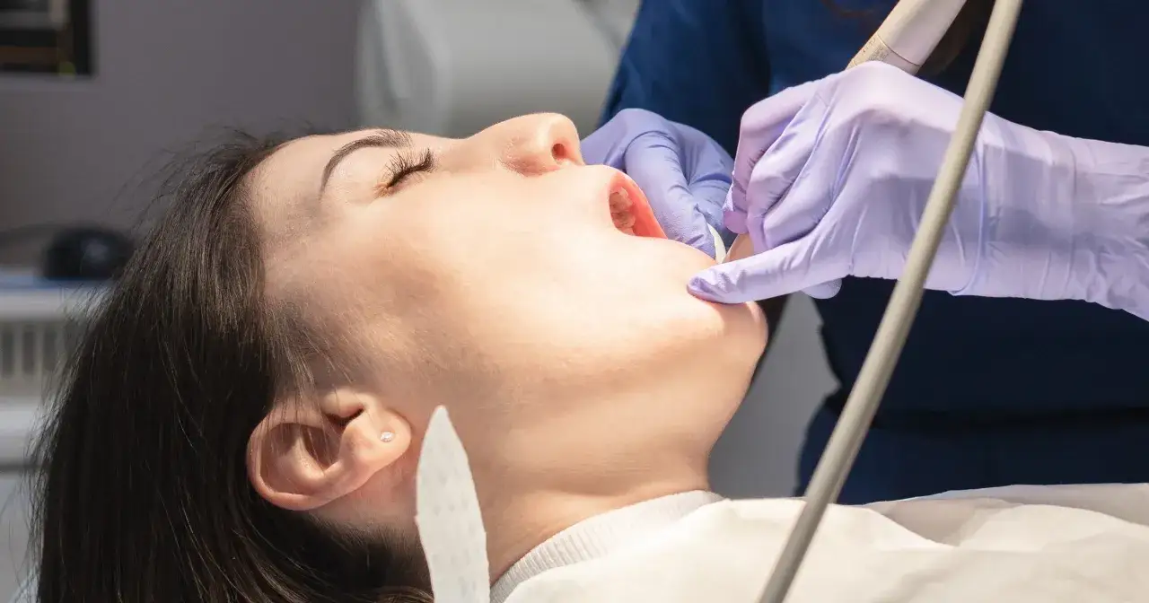 Dentysta pomaga zabezpieczyć ząb po wypadnięciu plomby, używając narzędzi stomatologicznych.