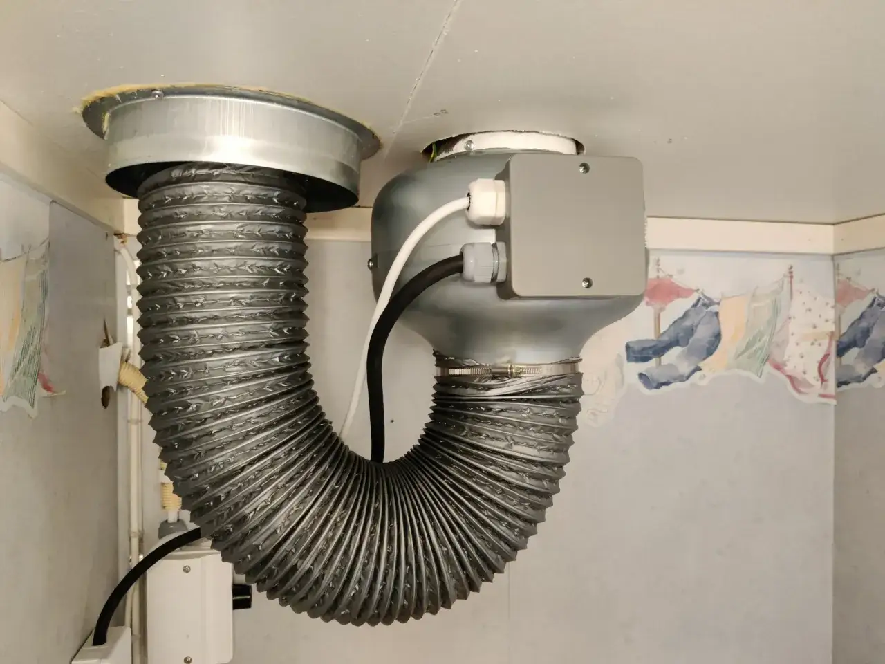 Ventilation ljudd&auml;mpare 125 mm, en flexibel slang ansluten till en fl&auml;kt med en gr&aring; kopplingsdosa.