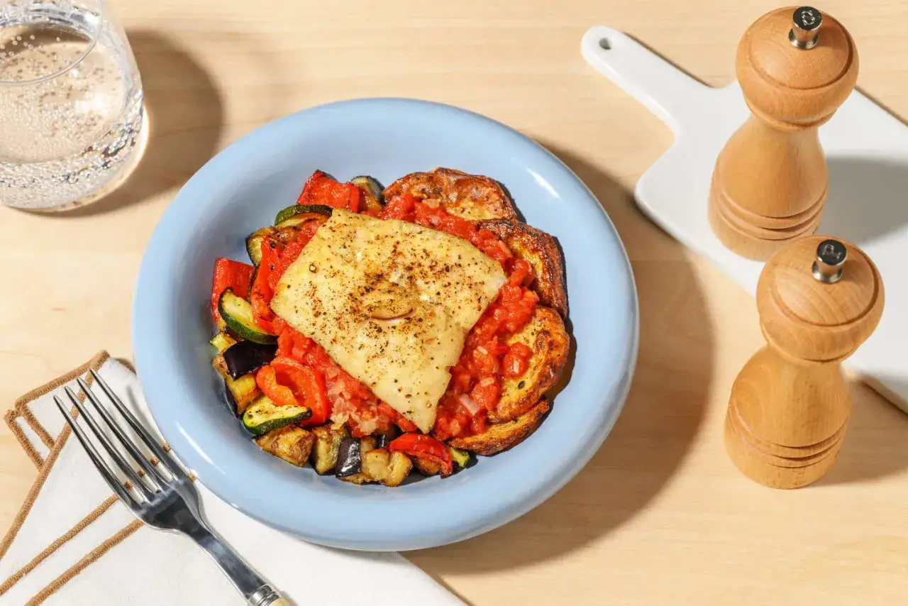 Filete de pescado con verduras asadas y salsa de tomate, una comida saludable que te encantará si buscas un coach de nutrición.
