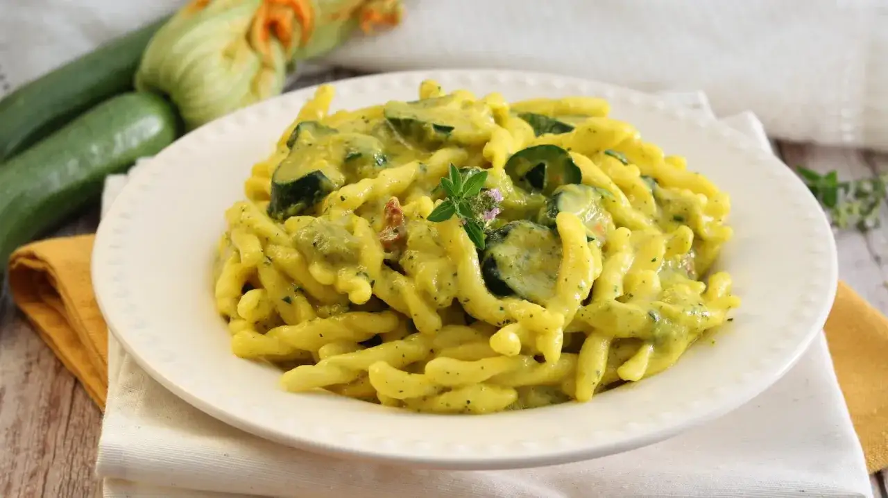 Un piatto invitante di pasta con zucchine e zafferano, guarnito con erbe aromatiche fresche.