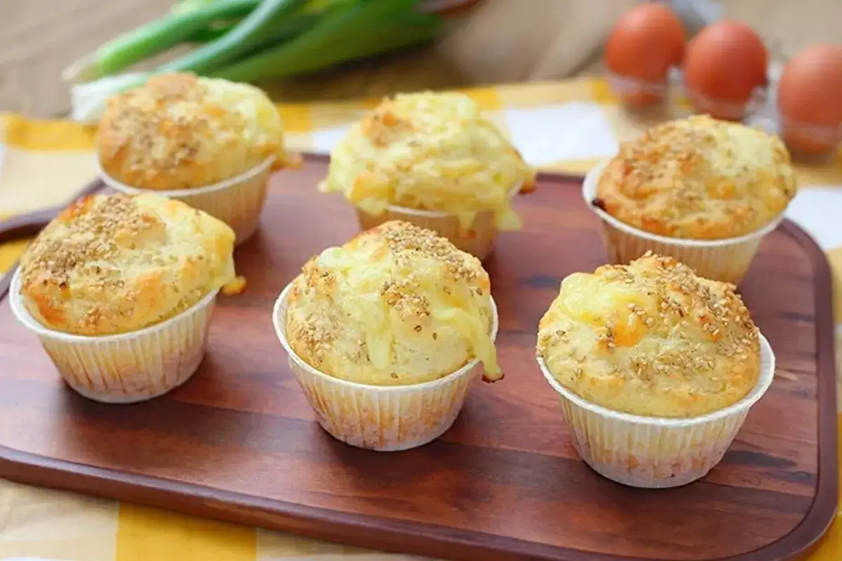 Sei muffin salati, con formaggio fuso e semi di sesamo, pronti per essere gustati. L'impasto per muffin è soffice e dorato.