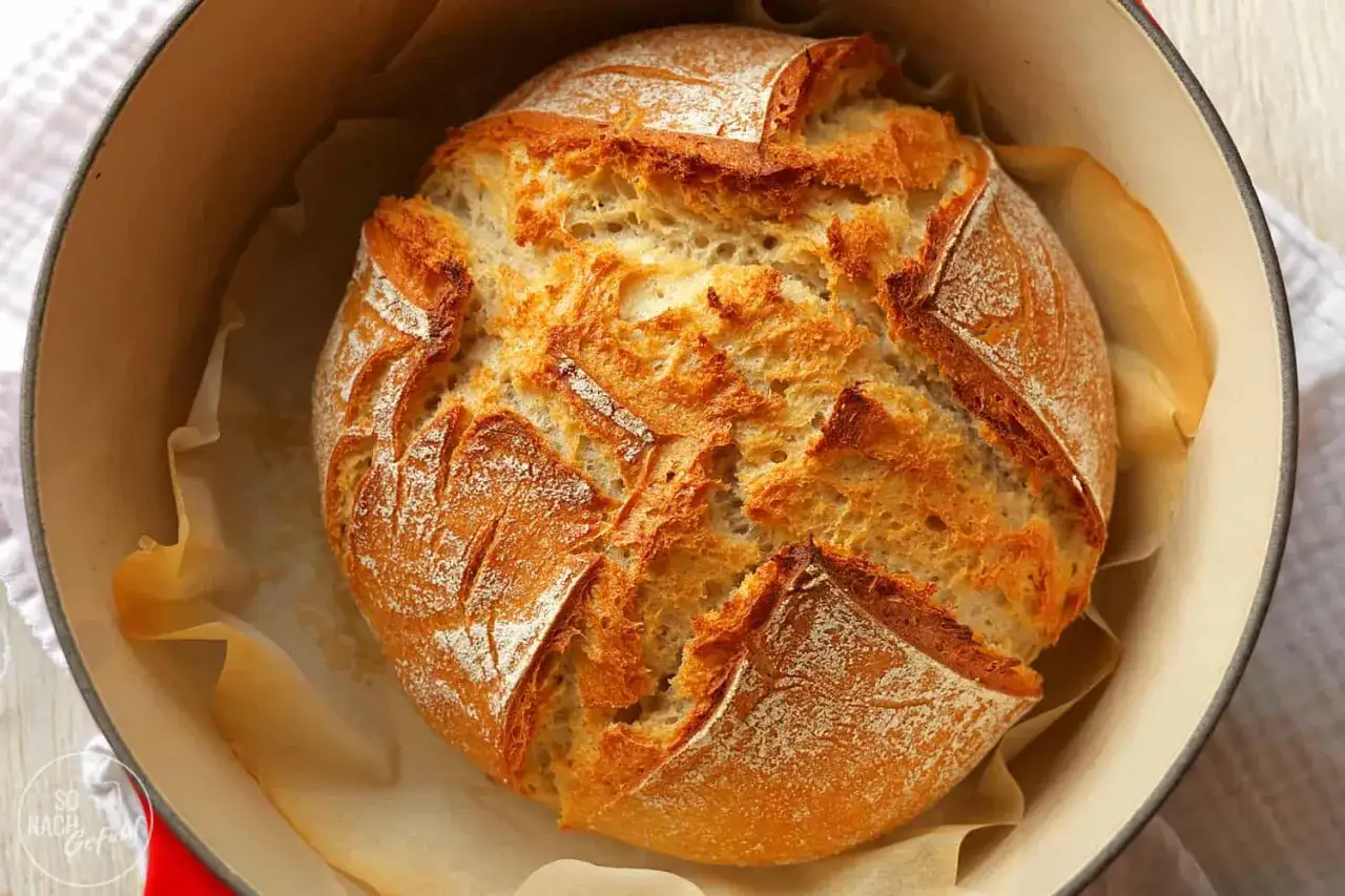 Frisch gebackenes Dinkelbrot mit knuspriger Kruste liegt in einem Gusseisentopf. Perfekt zum dinkelbrot backen!