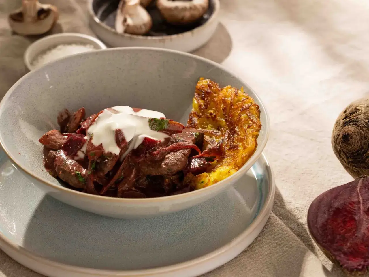 Herzhaftes Rindergulasch mit Roter Bete und einem Klecks Sauerrahm, serviert mit knusprigen R&ouml;sti. Ein authentisches stroganoff rezept original.