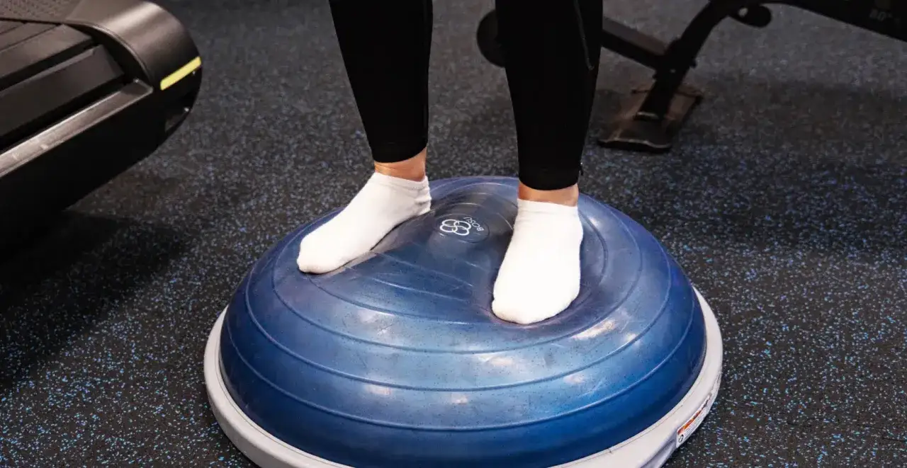 Personne en chaussettes blanches s'entra&icirc;nant sur un ballon BOSU. Peut-&ecirc;tre pour d&eacute;terminer combien de s&eacute;ance de kin&eacute; pour entorse cheville.