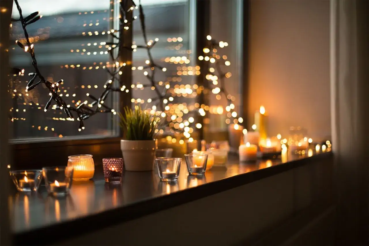 Ljusslingor och levande ljus skapar en mysig julst&auml;mning vid f&ouml;nstret.
