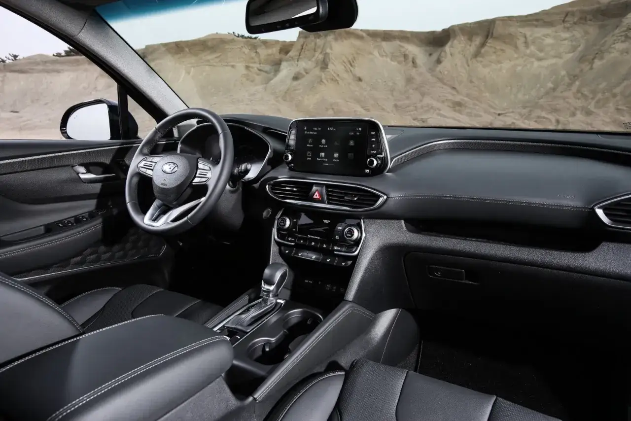 Wnętrze nowego Hyundai Santa Fe 2025 z czarną tapicerką, nowoczesnym ekranem multimedialnym i kierownicą.