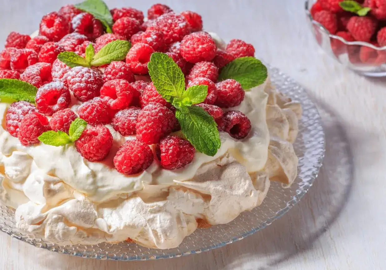 Beza pavlova która zawsze wychodzi, obficie udekorowana malinami i listkami mięty. Idealna na deser.