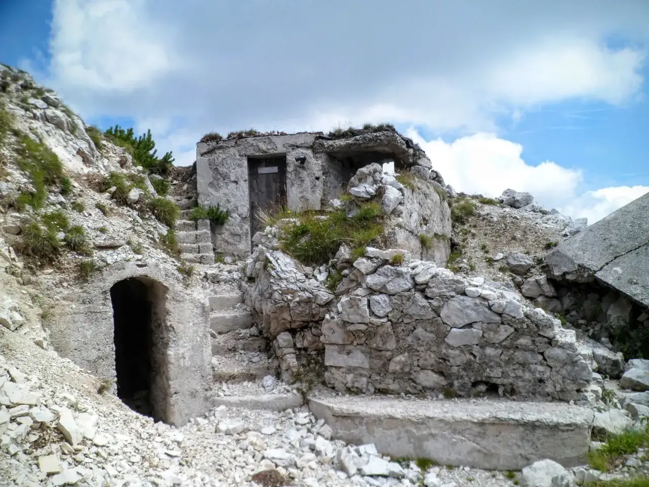 Rovine di un bunker in montagna, con scale di pietra e un ingresso buio. Un luogo che evoca storie di val saisera.