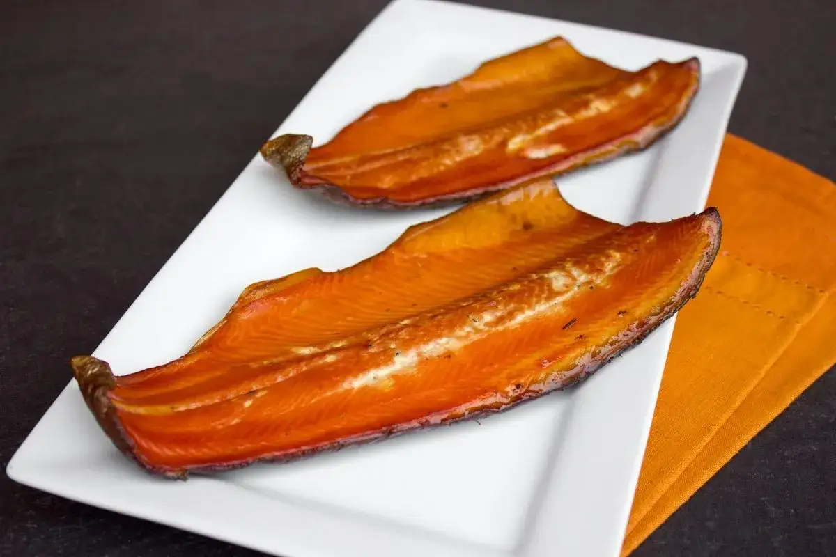 Deux filets de truite fumée, dorés et appétissants, sur une assiette blanche. Parfait pour le temps de fumage.
