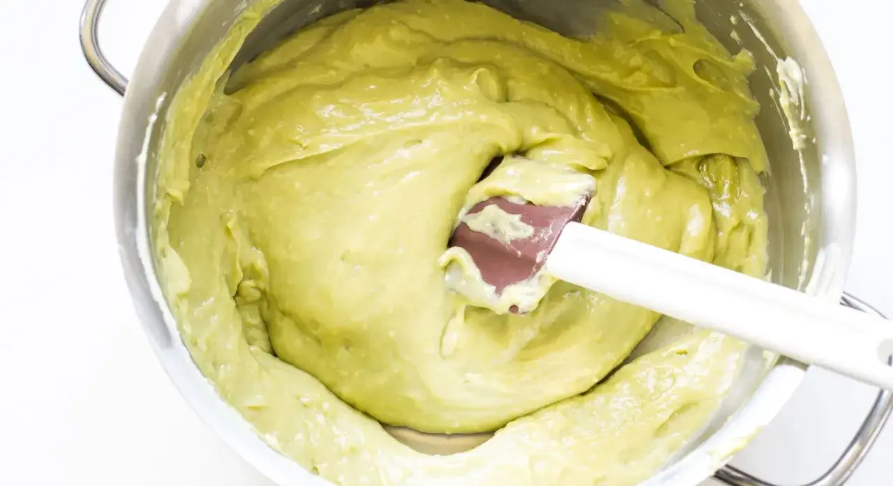 Impasto cremoso di pasta di pistacchio in una ciotola d'acciaio, pronto per essere utilizzato in dolci deliziosi.
