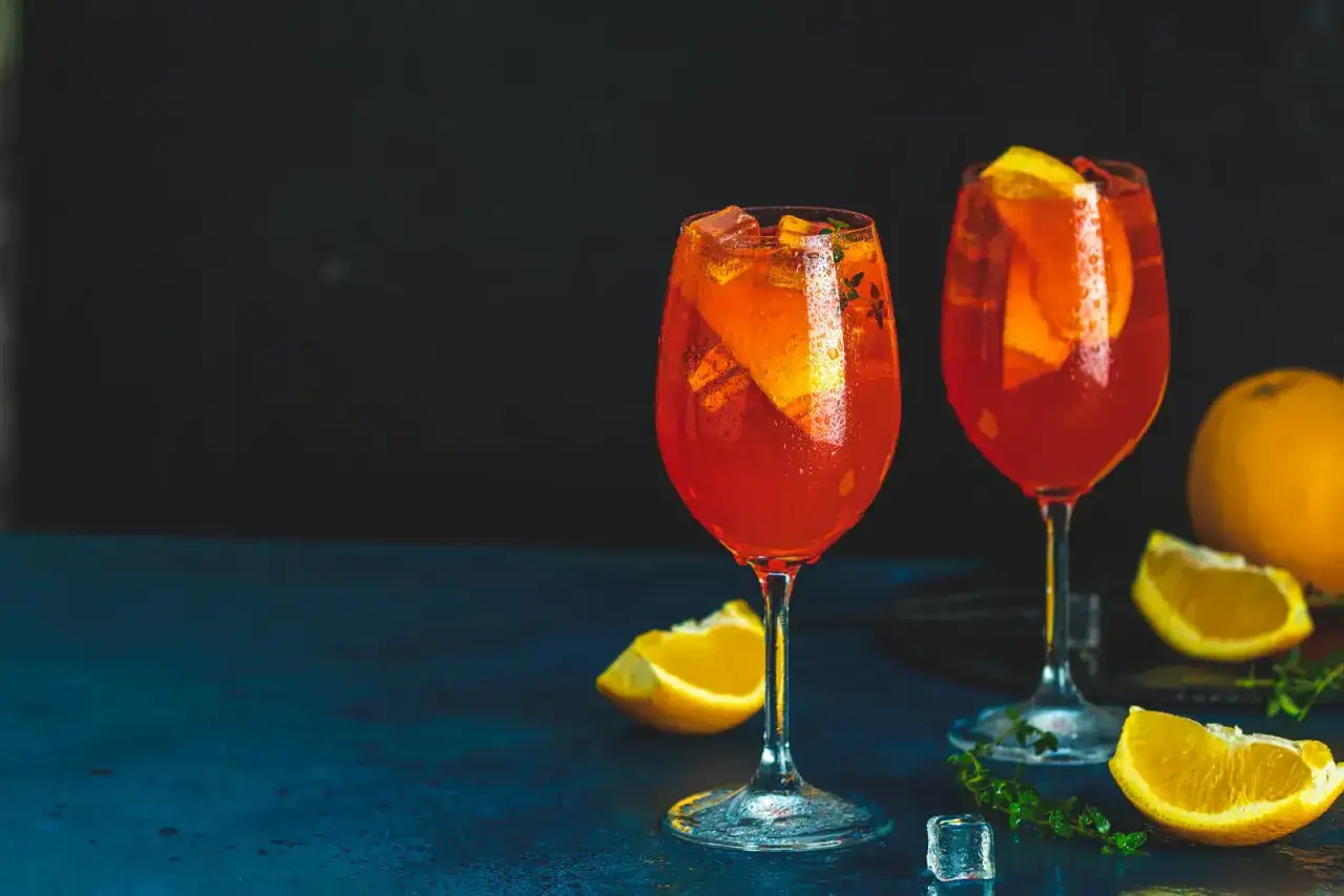 Dwa Aperol Spritz z pomarańczą i lodem. Idealne na lato, gdy zastanawiasz się, aperol z czym pić.