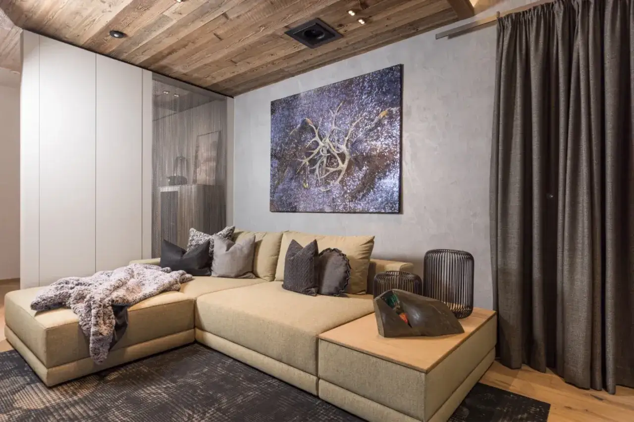 Gem&uuml;tliches Wohnzimmer mit beigem Ecksofa, Kunstwerk an der Wand und Holzbalkendecke. Tolle Einrichtungstipps f&uuml;r ein stilvolles Zuhause.