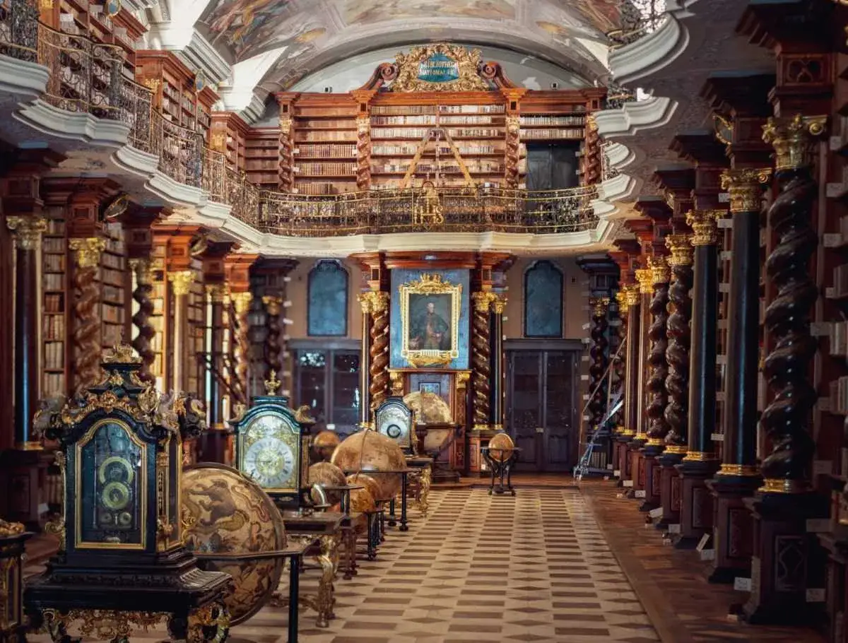 Wspaniała sala biblioteczna, gdzie antyczne globusy i zegary stoją wśród regałów pełnych ksiąg. To serce biblioteki narodowej Republiki Czeskiej.