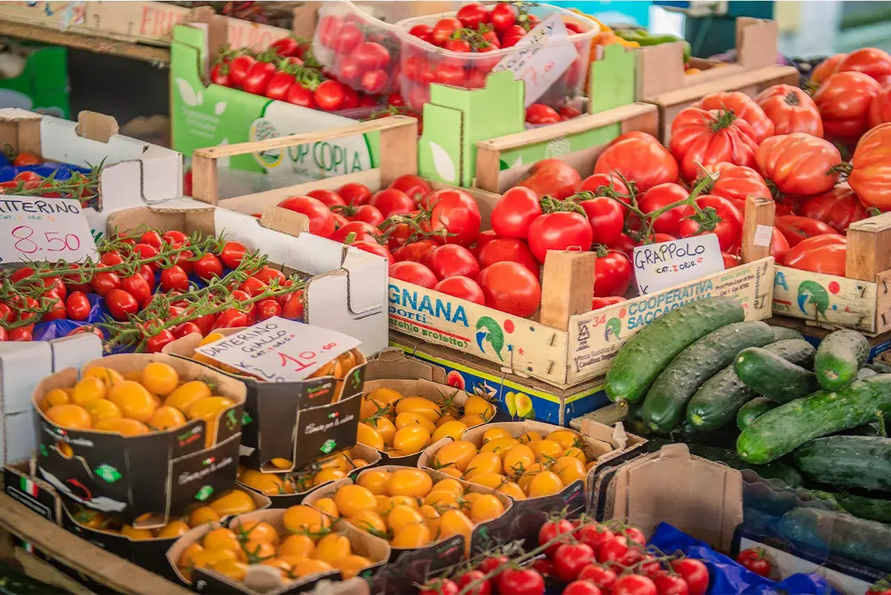 Pomodori rossi e gialli, cetrioli e altre verdure fresche in un colorato mercato di Venezia.
