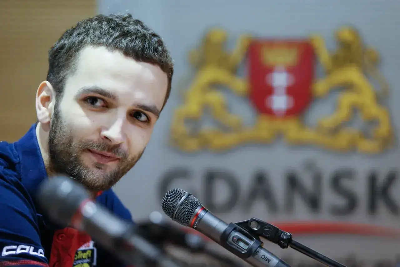 Mateusz Mika, znany siatkarz, przed mikrofonem. W tle herb Gdańska, miasta, gdzie gra.