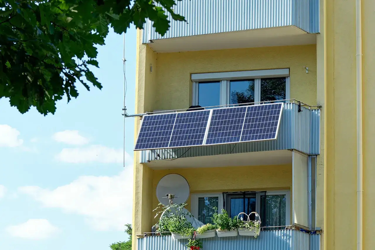 Tv&aring; balkong solceller f&aring;ngar solljuset p&aring; en gul byggnad. Gr&ouml;na v&auml;xter pryder balkongr&auml;cket nedanf&ouml;r.