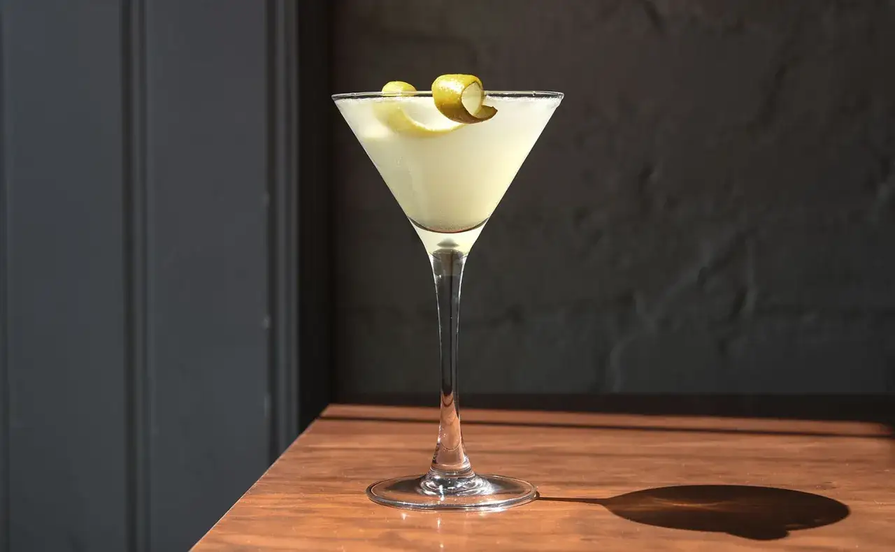 En elegant gin sour i ett martiniglas, garnerad med en citronskalsslinga. Perfekt f&ouml;r en solig eftermiddag.
