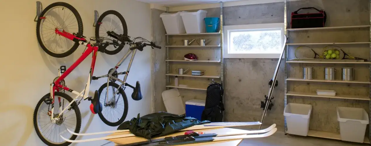 Deux v&eacute;los suspendus, skis, raquettes et bo&icirc;tes de rangement. Une astuce rangement v&eacute;lo garage efficace pour optimiser l'espace.
