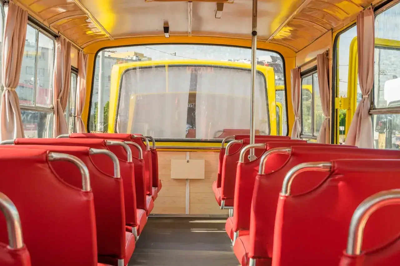 Wnętrze żółtego autobusu z czerwonymi siedzeniami. Zastanawiasz się, po jakim czasie przedawnia się mandat za brak biletu?