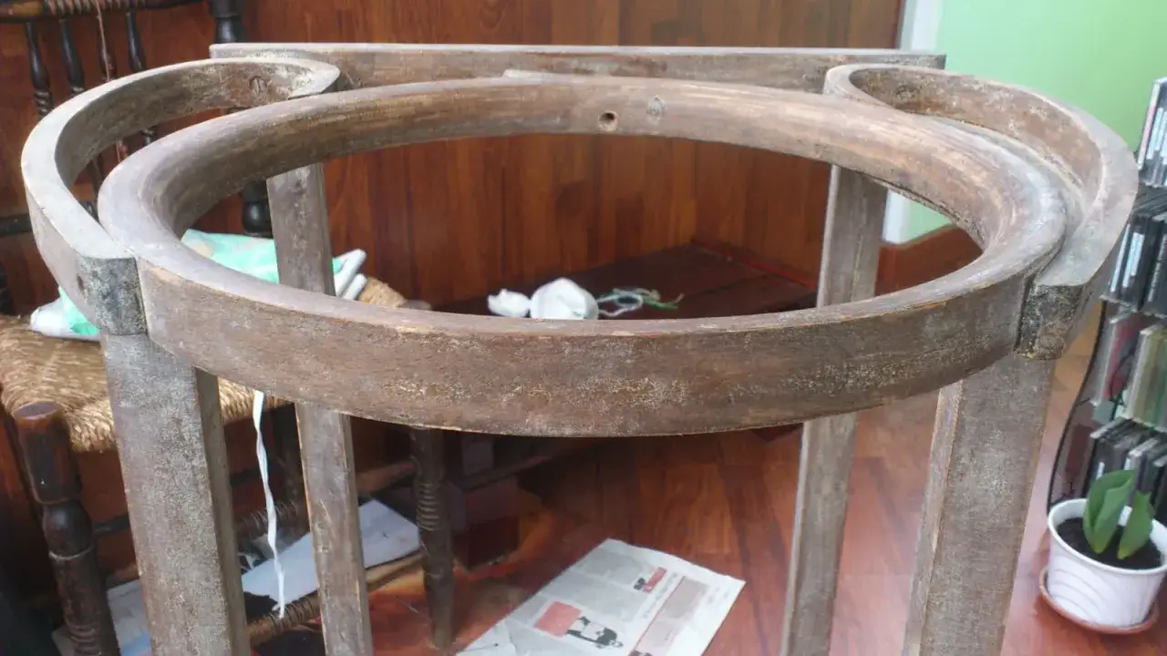 Estructura de madera de un palanganero antiguo, lista para restaurar. Se aprecian sus patas y el aro superior curvo, desgastados por el tiempo.