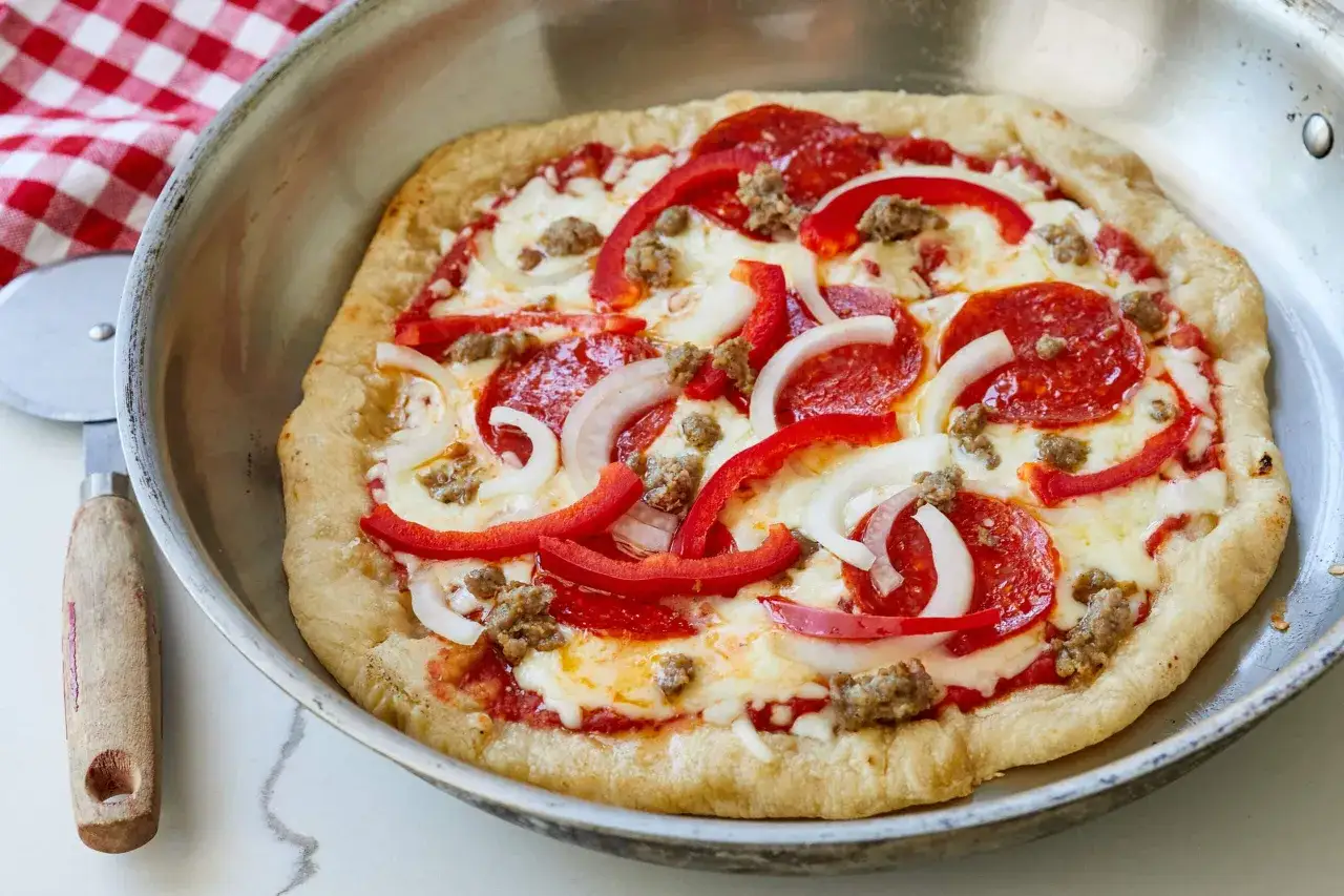 Pyszna pizza z patelni z kiełbasą, papryką i cebulą, gotowa do pokrojenia.