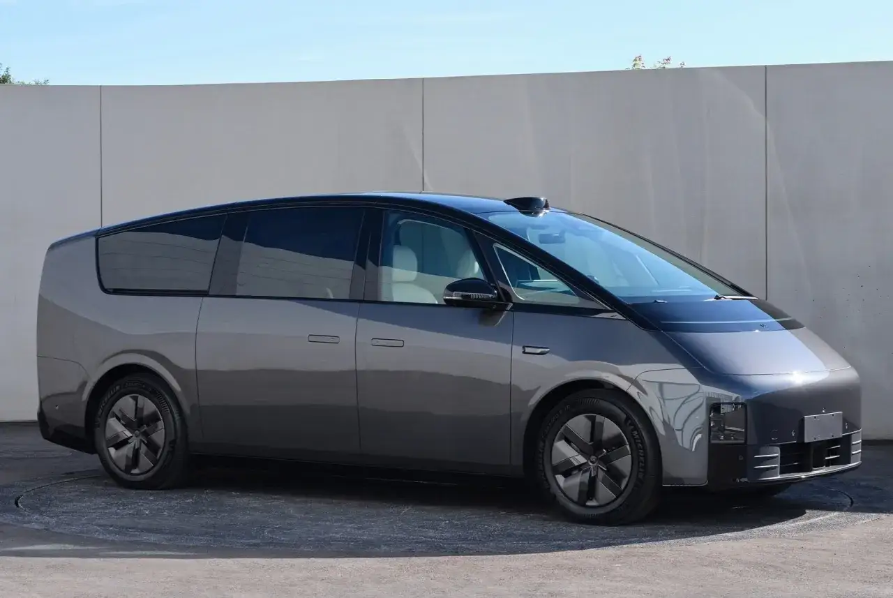 Un concept de li auto gris futuriste, avec un toit noir et des vitres teintées, se tient devant un mur blanc.