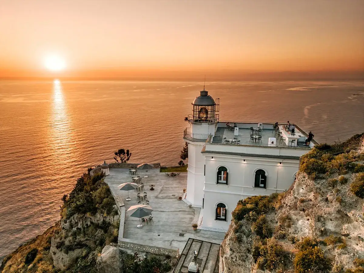 Tramonto mozzafiato sul mare visto dall'hotel Faro Punta Imperatore a Ischia. Tavolini all'aperto e un bar sul tetto invitano a godersi la vista.