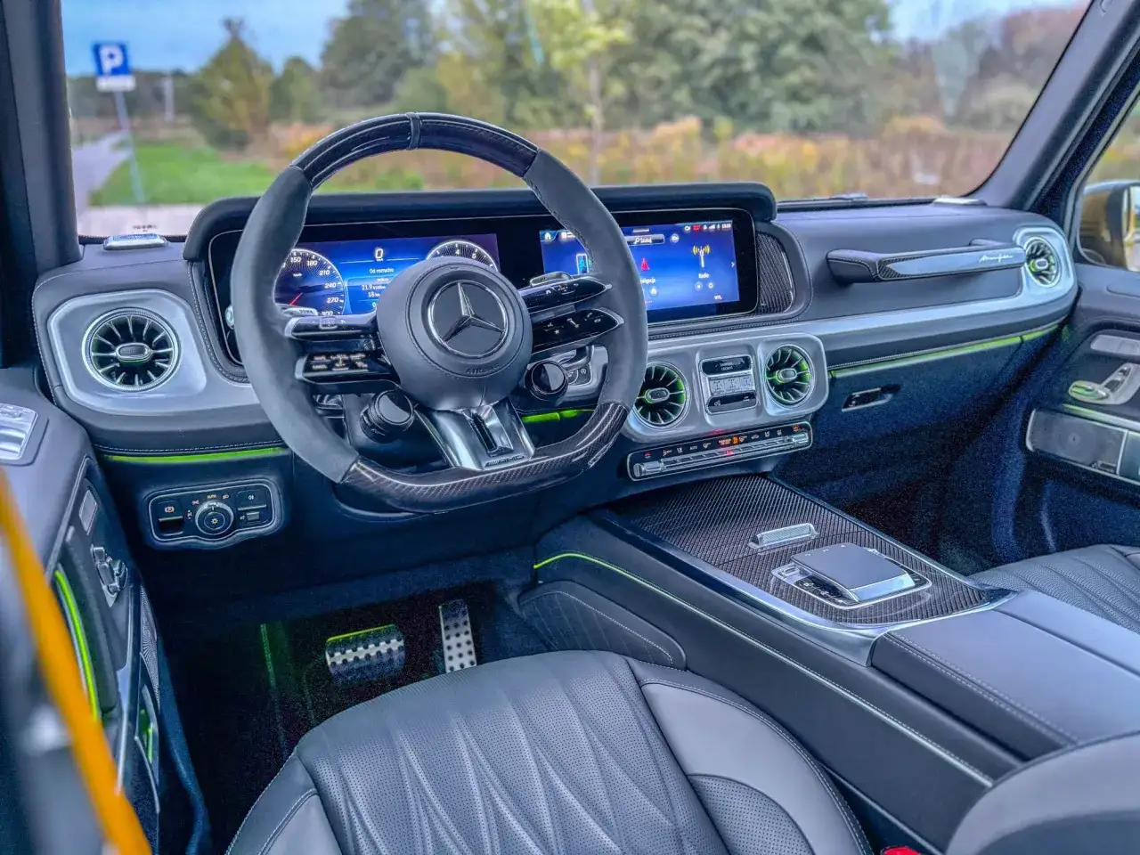 Wnętrze luksusowego g wagon z nowoczesnym kokpitem, cyfrowymi ekranami i sportową kierownicą.