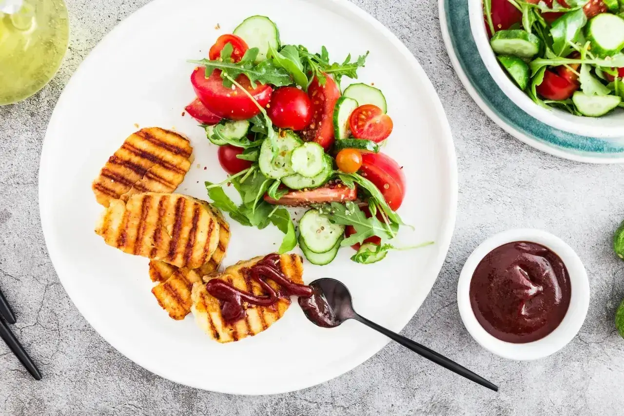 Grillowany ser halloumi z sosem barbecue i świeżą sałatką z pomidorów i ogórków.