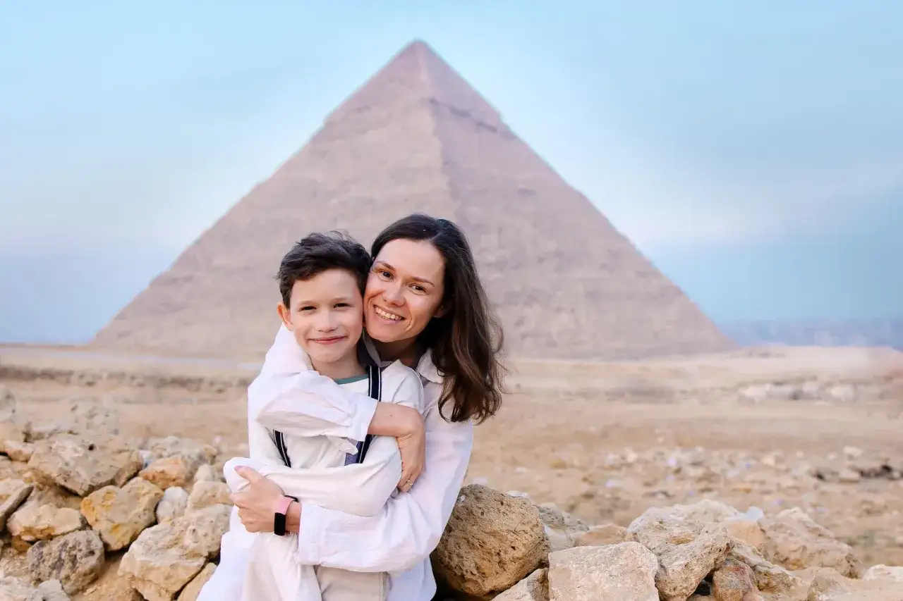Madre e hijo sonríen frente a una pirámide, un recuerdo perfecto de la mejor época para viajar a Egipto.