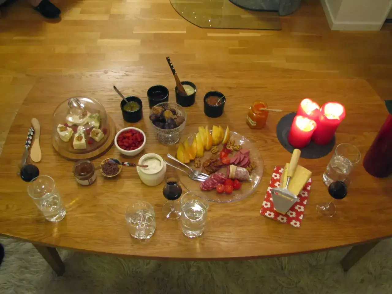 En härlig ostbricka jul med godsaker som nötter, frukt, korv och olika röror. Tre röda ljus lyser upp bordet.