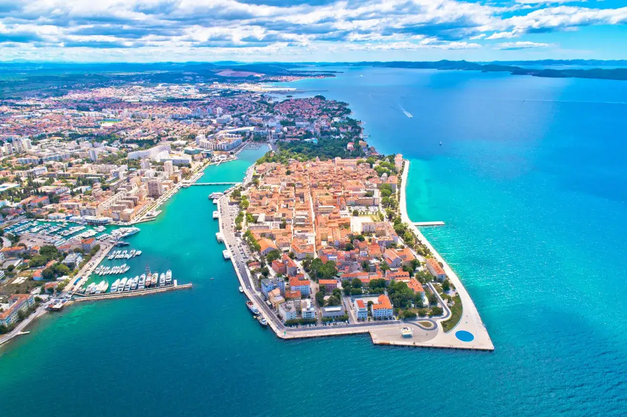 Zadar ceny nocleg&oacute;w i atrakcji zachęcają do odkrywania tego pięknego chorwackiego miasta. Widok z lotu ptaka na star&oacute;wkę i turkusowe morze.