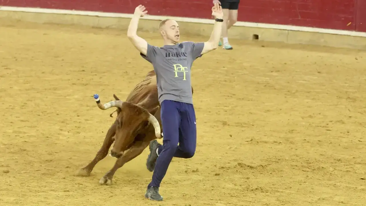 Un hombre corre asustado de un toro en la arena, un momento de tensión en el **Grand Prix Zaragoza**.