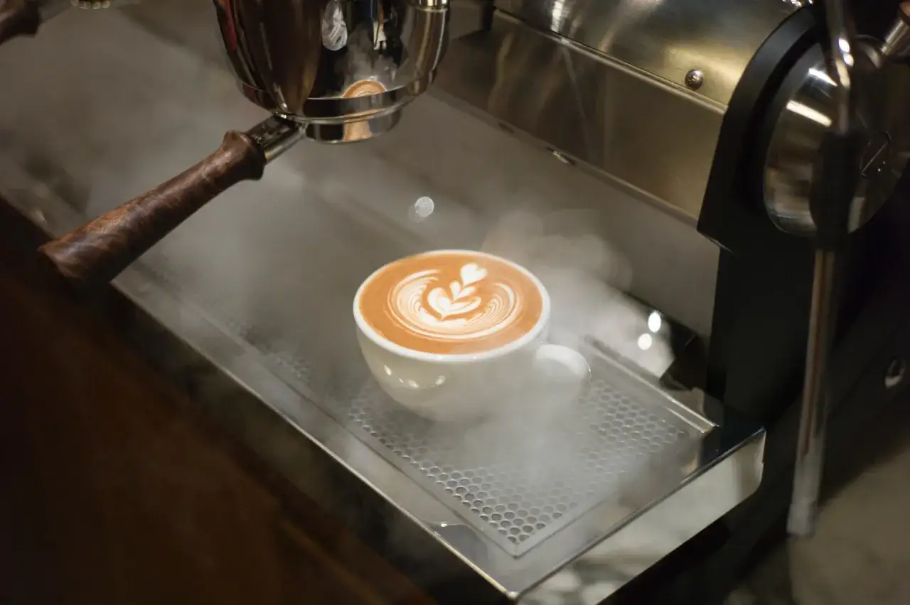 En vacker latte med hjärtmönster ångar på en espressomaskin. Perfekt för en mysig latte hemma.