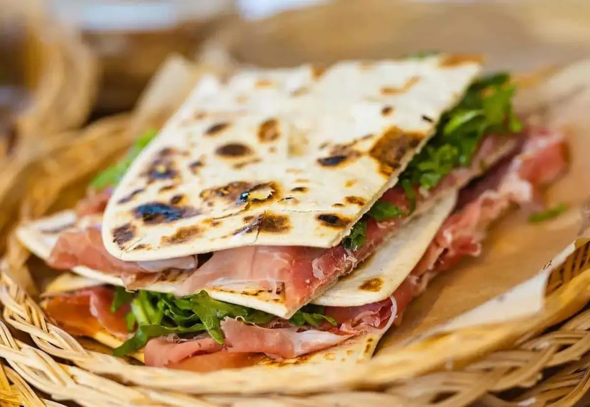 Piadina romagnola, il piatto tipico di Rimini, con prosciutto crudo e rucola, servita in un cestino di vimini.